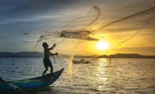 Pescatore getta una rete in mare
